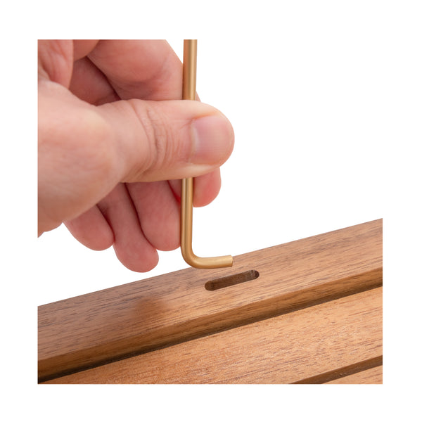 A close-up of a hand inserting a long rod into a wooden panel, set against a plain white background.