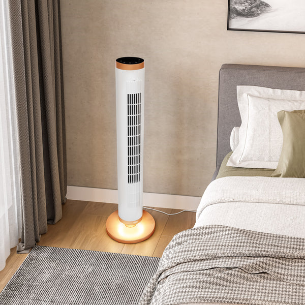 A white tower fan with a copper top and base sits on a wooden floor next to a bed in a modern bedroom setting.