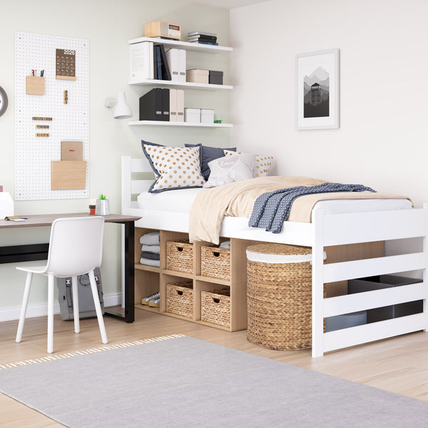 A white wooden loft bed with integrated storage cubbies and a slatted headboard, styled in a bright, modern bedroom with a desk, chair, and gray rug.