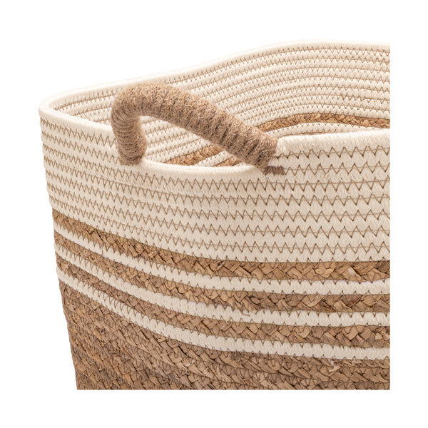 A close-up of a woven storage basket with a thick rope handle, featuring horizontal stripes in cream, beige, and natural brown on a white background.